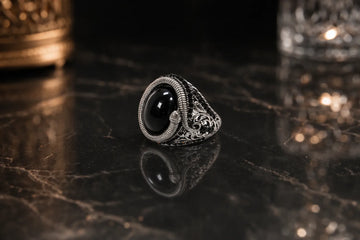 Silver ring with a black stone encircled by a snake